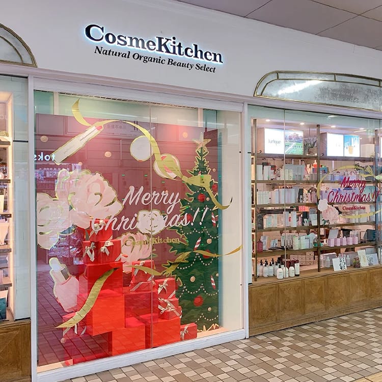 cosme-kitchen-daikanyama-1 - SomethingBeautiful!! CosmeKitchen storefront with Christmas window art, including a Christmas tree and red gift boxes in the display window, plus store sign above.