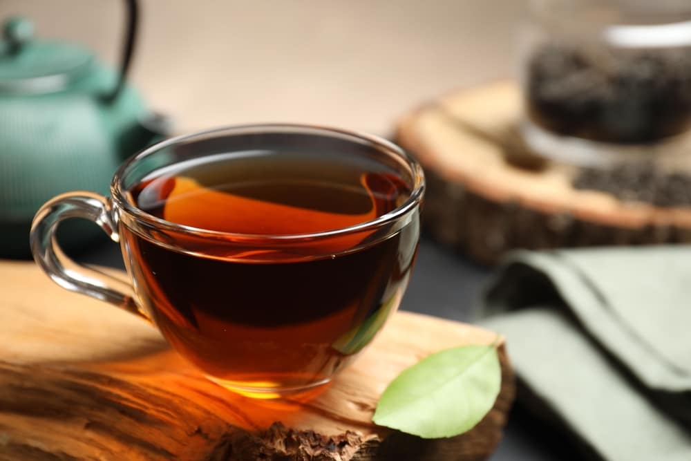 AromaticBlackTeaInCupAndGreenLeafOnWooden - SomethingBeautiful!!