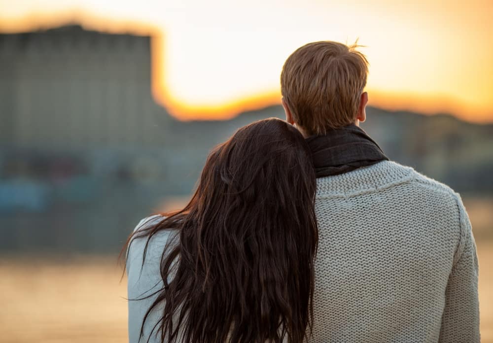 YoungCoupleFromBehindEnjoyingPeacefulSunsetViewNearWater - SomethingBeautiful!!