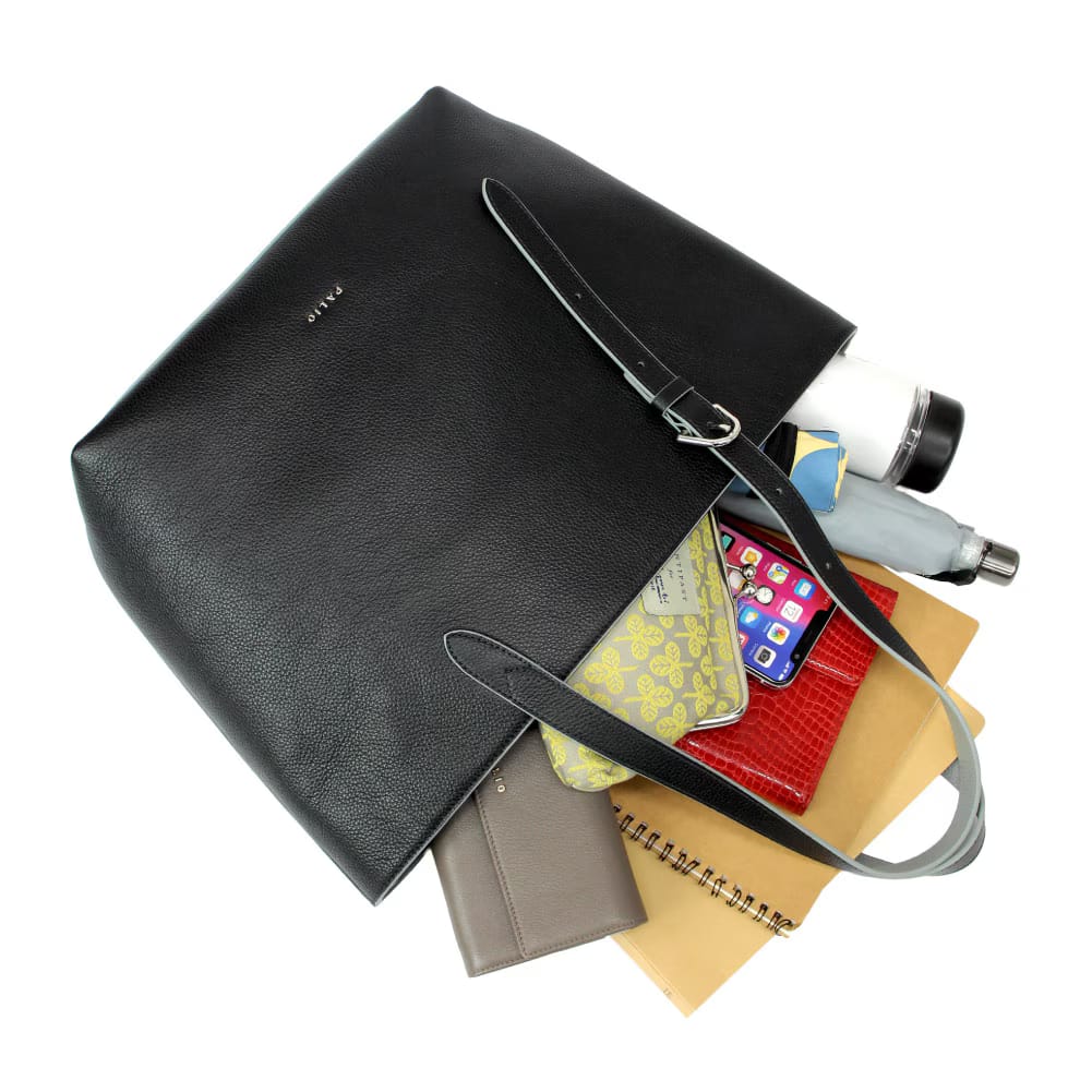11_000000001358 - SomethingBeautiful!! Black tote bag with multiple items spilling out: notebook, wallet, phone, water bottle, and folders inside.