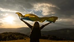 beautiful-young-woman-flag-ukraine-250nw-2611579031 - SomethingBeautiful!! Silhouette of a person on a hillside at sunset, arms raised with a scarf fluttering in the wind.