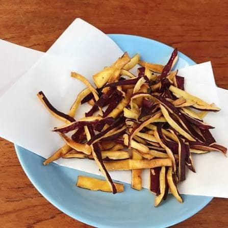 images - 2026-09-18T013916699 - SomethingBeautiful!! Blue plate holding a mound of thin-cut fries—yellow and purple sweet potato varieties—placed on white parchment on a wooden table.