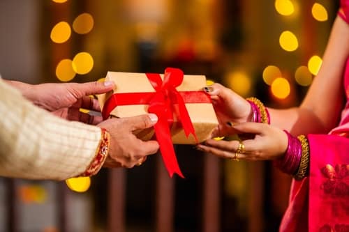 HandingWrappedGiftBoxToWomanCelebratingDiwaliFestivalWith - SomethingBeautiful!!