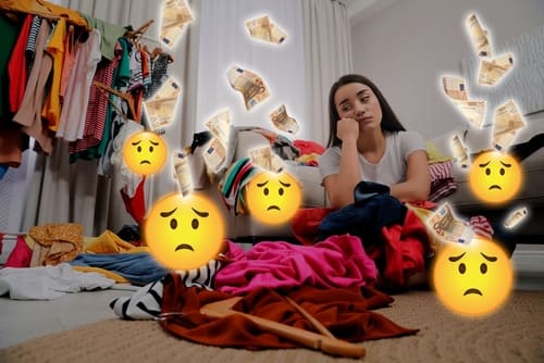 BuyersRemorseUpsetWomanWithManyClothesRegrettingAboutWasting - SomethingBeautiful!! A young woman sits on a cluttered bedroom floor with hanging clothes and piles of fabric, looking distressed as money bills float around her.