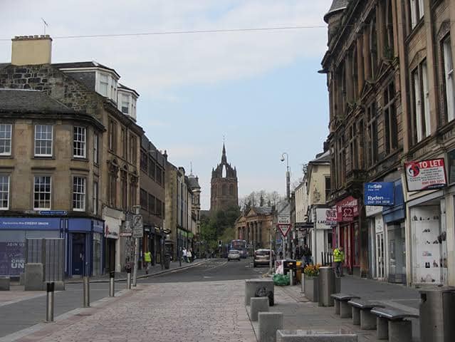 images - 2026-09-29T014845541 - SomethingBeautiful!! A cobblestone street lined with historic shops and stone buildings, leading to a church with a tall spire in the distance.