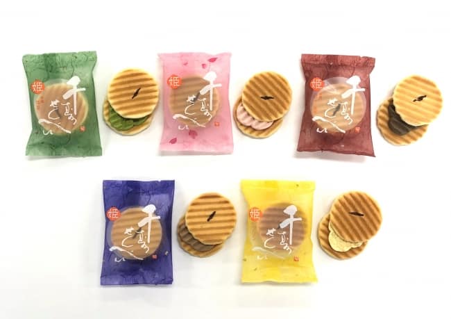 d8274-90-295609-2 - SomethingBeautiful!! Assorted wafer cookies placed between colorful packaged snacks on a white surface in two rows.